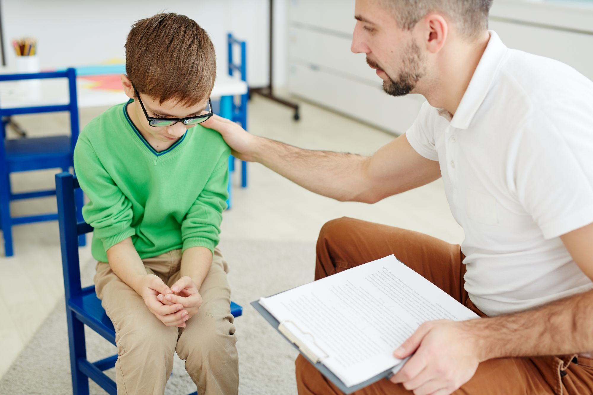 De-escalation - Chapter 5 - School psychologist touching shoulder of frustrated schoolboy while trying to help him